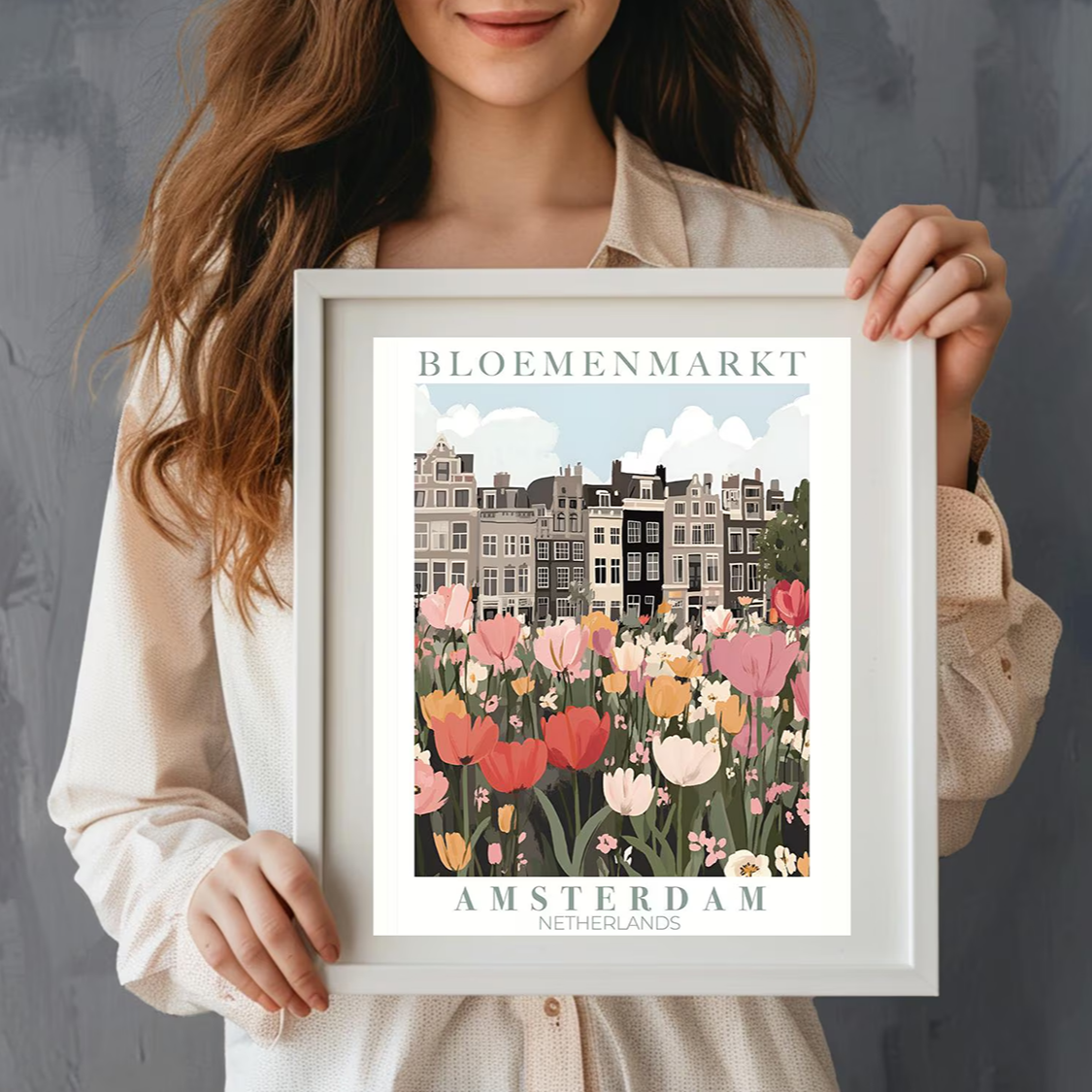 Woman holding a framed print of Bloemenmarkt, Amsterdam with colorful flowers and buildings.