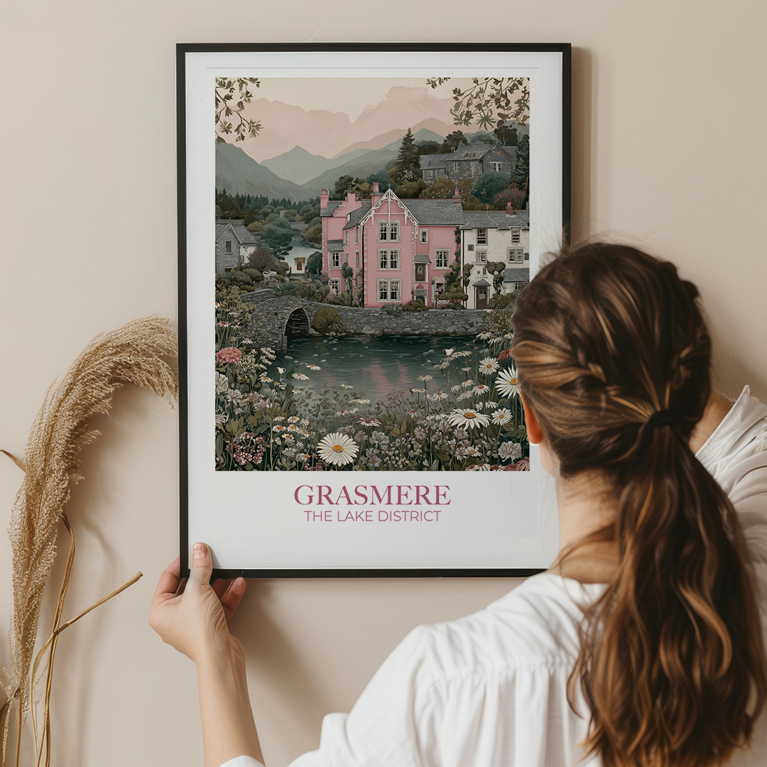 Woman holding a framed print of Grasmere, The Lake District against a beige wall.