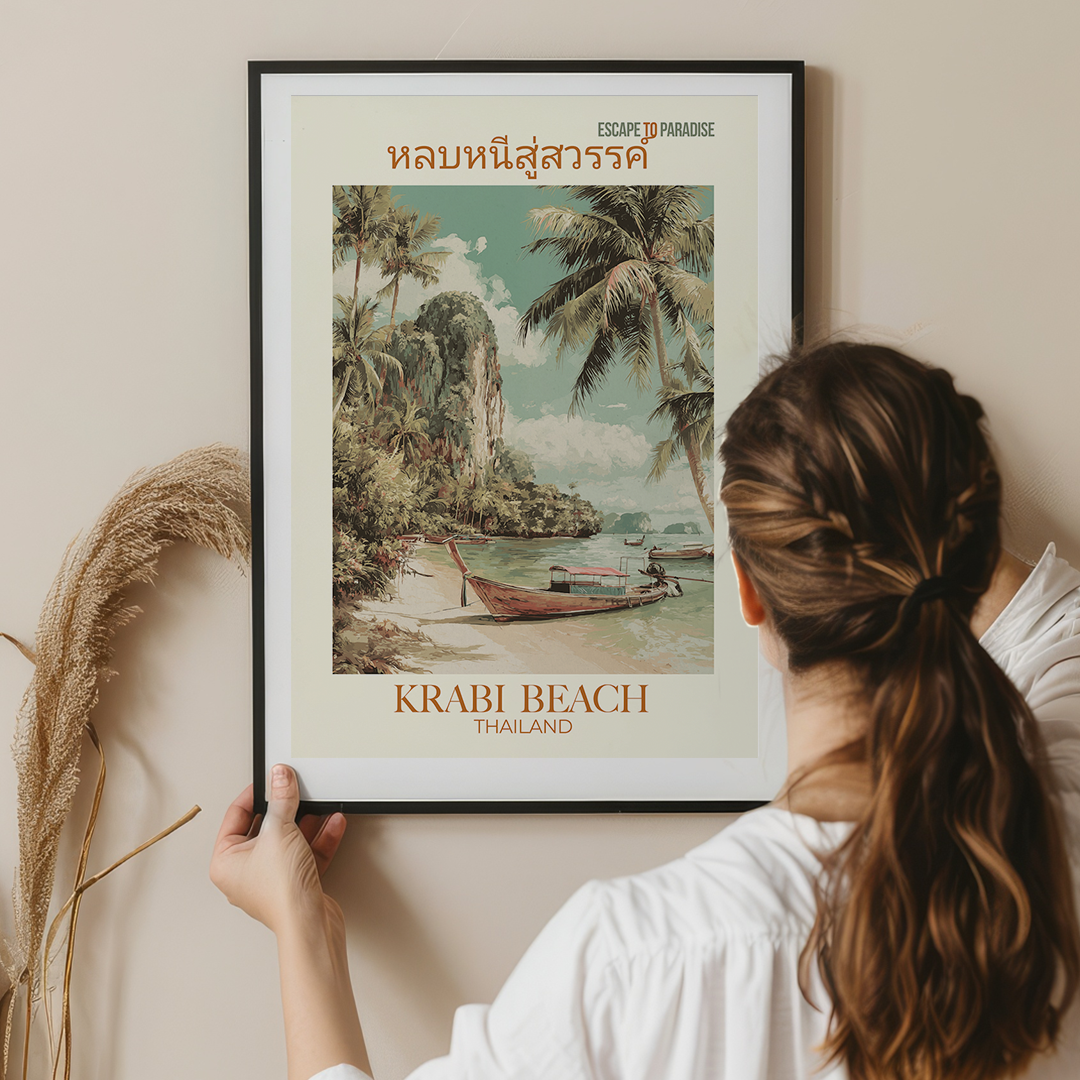 Person hanging a framed poster of Krabi Beach, Thailand on a wall.