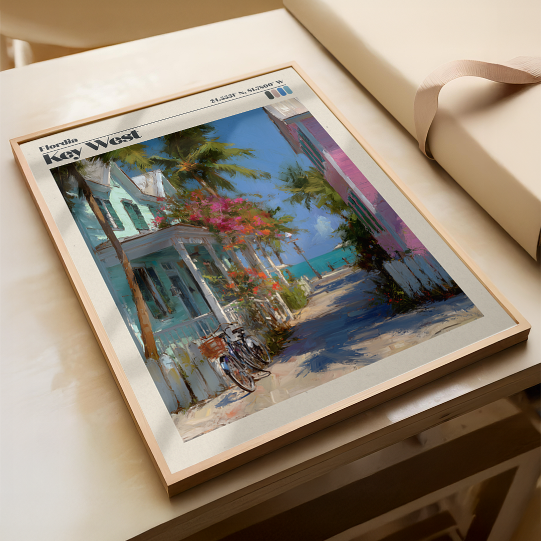 Framed painting of a street scene with palm trees and colorful buildings on a light wooden surface.