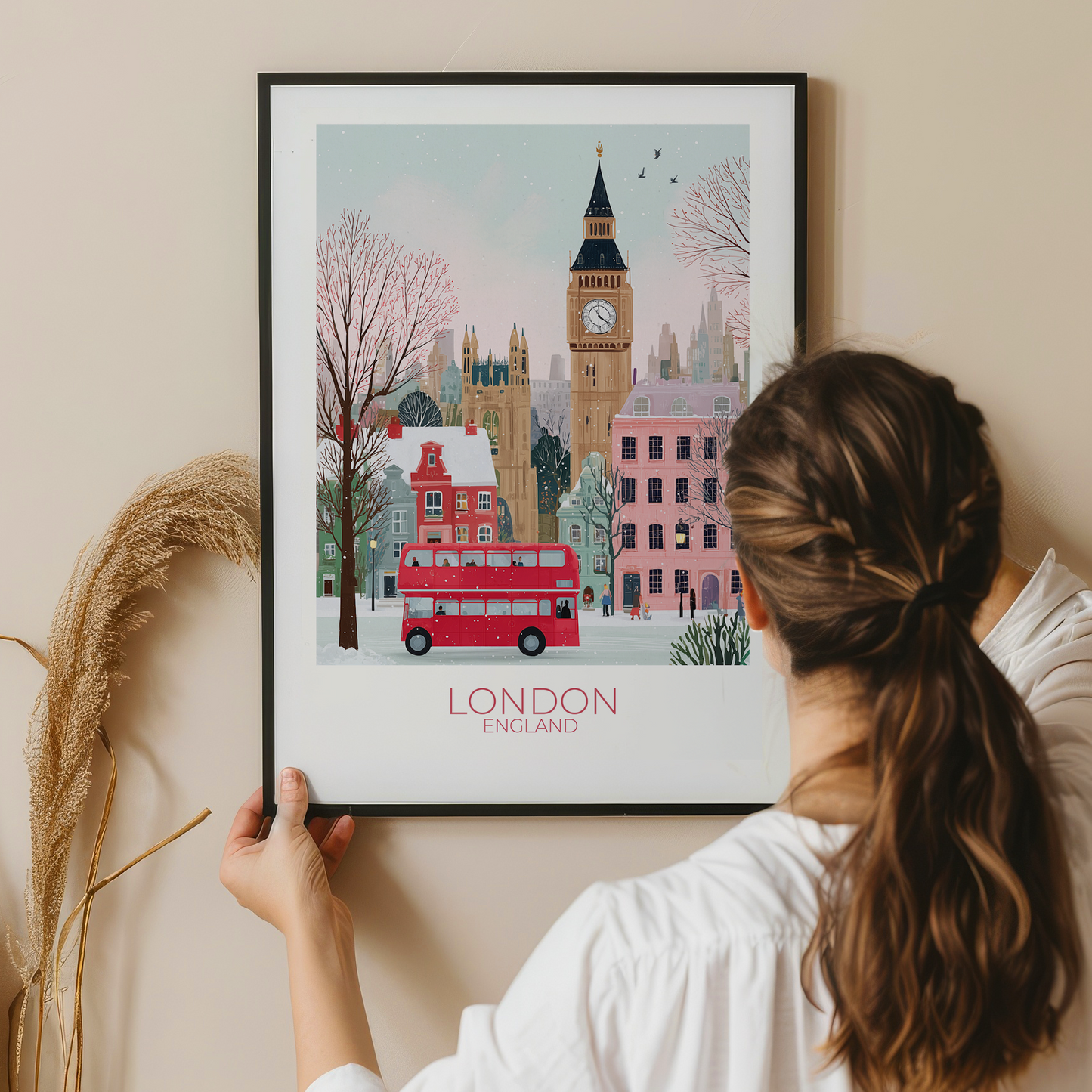 Person holding a framed print of London with Big Ben and a red double-decker bus.