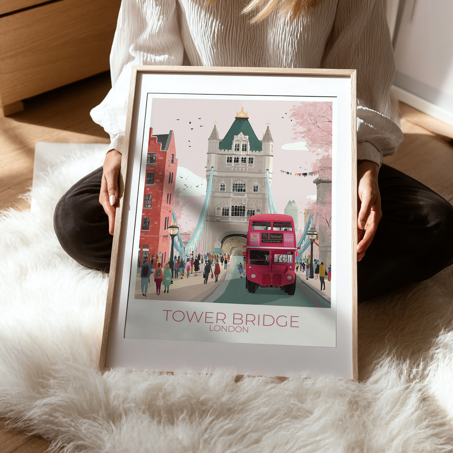 Framed artwork of Tower Bridge and a red double-decker bus being held on a woman's lap to show detail