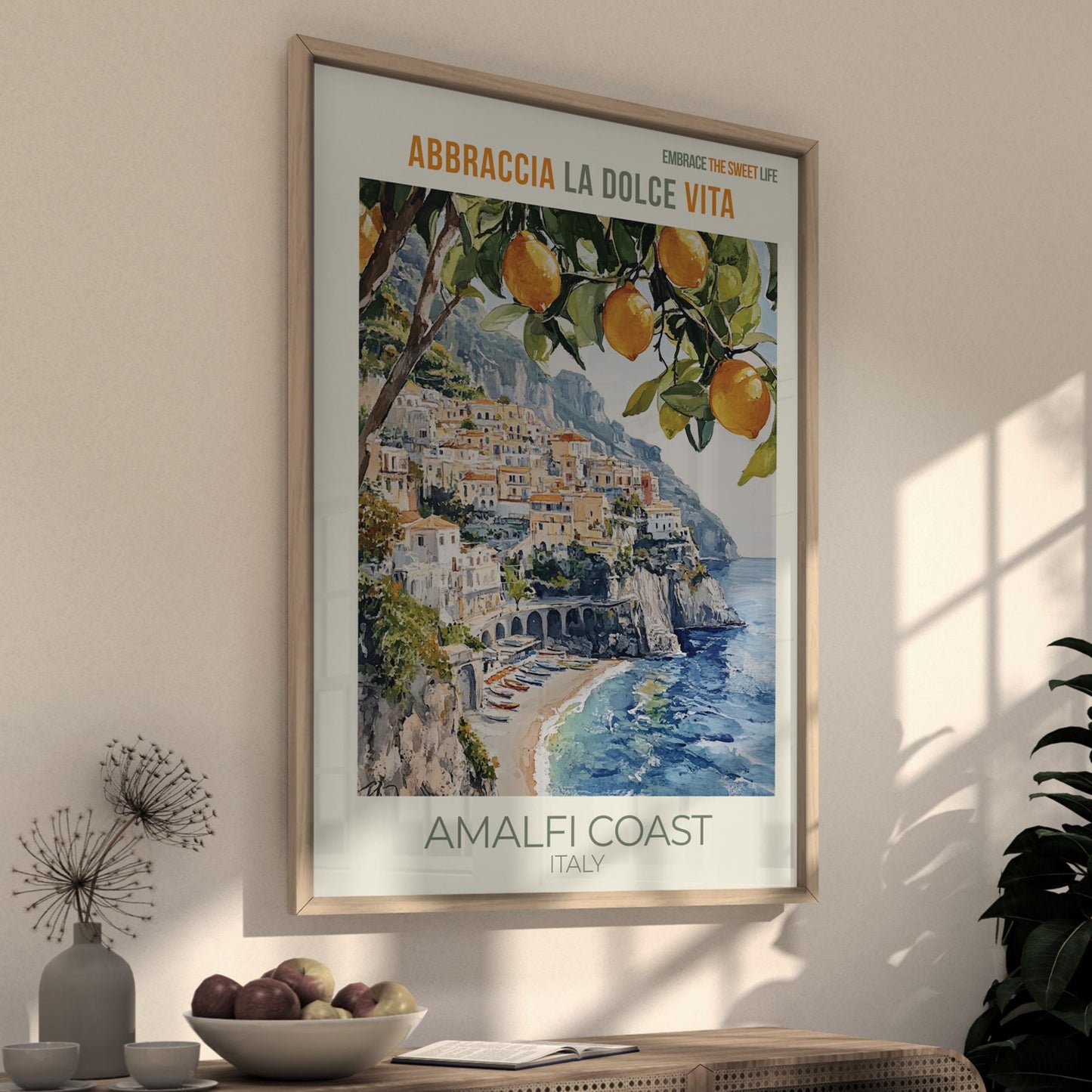 Framed poster of the Amalfi Coast with oranges on a wall in a room.