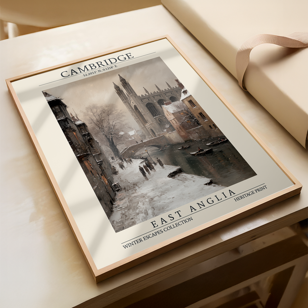 Framed print of a snowy scene with 'Cambridge' and 'East Anglia' text on a wooden surface.