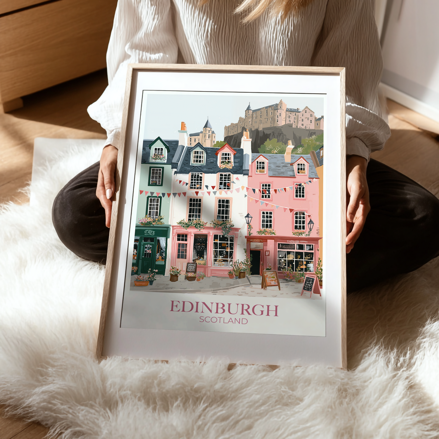 Person holding a framed print of Edinburgh, Scotland with colorful buildings and a castle.