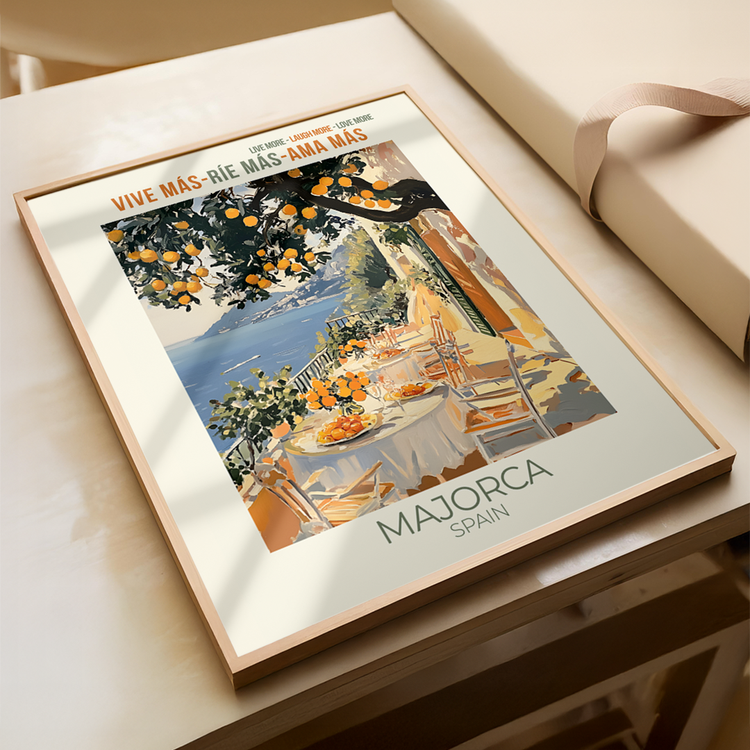 Framed artwork of a scenic table setting with oranges, labeled 'Majorca Spain', on a light wooden surface.