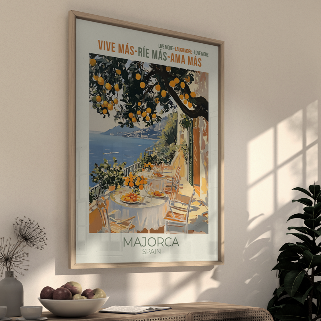 Framed artwork of a scenic view with text on a wall in a room with a plant and table.