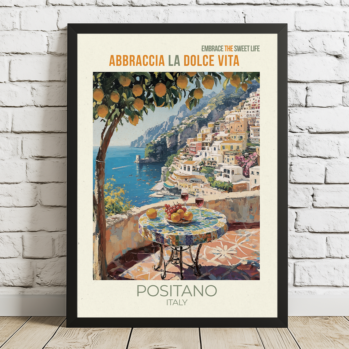 Framed artwork of Positano, Italy with a scenic view and text on a white brick wall.