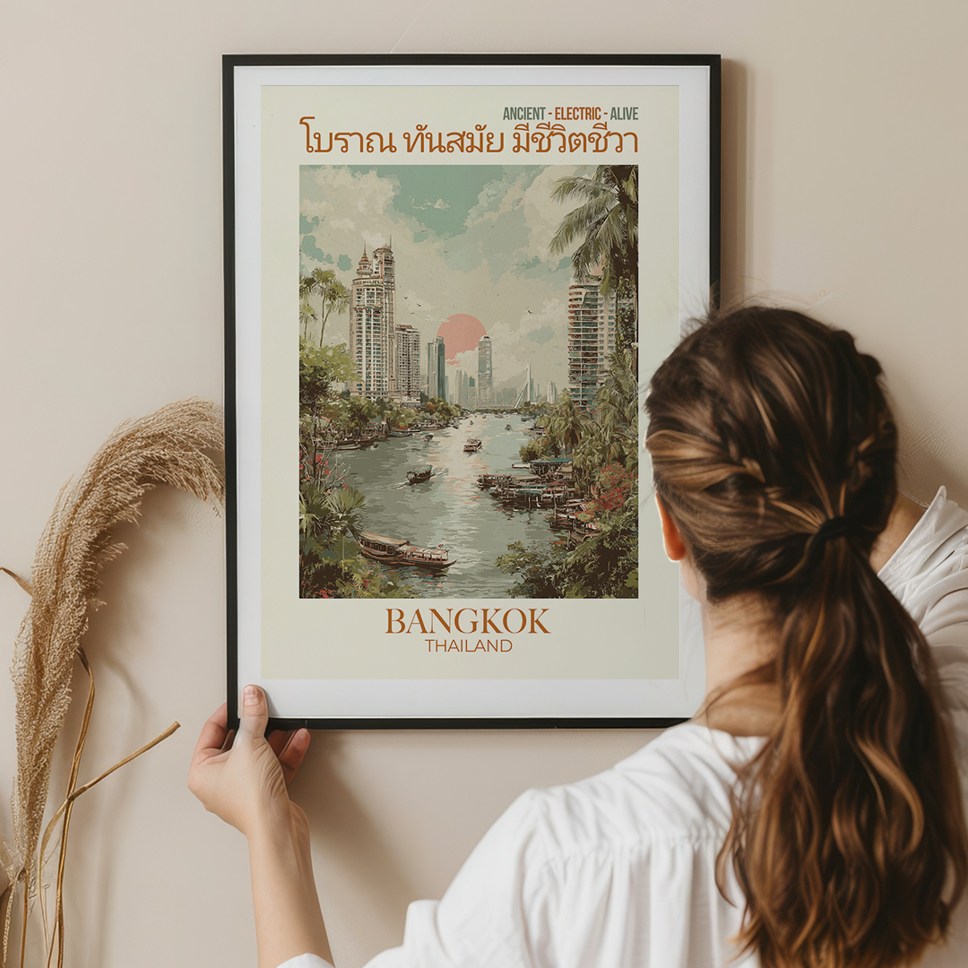 Person hanging a framed poster of Bangkok, Thailand on a wall.