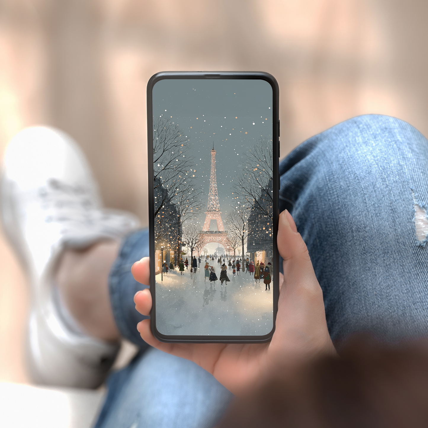 Person holding a phone showing the Eiffel Tower in a snowy scene