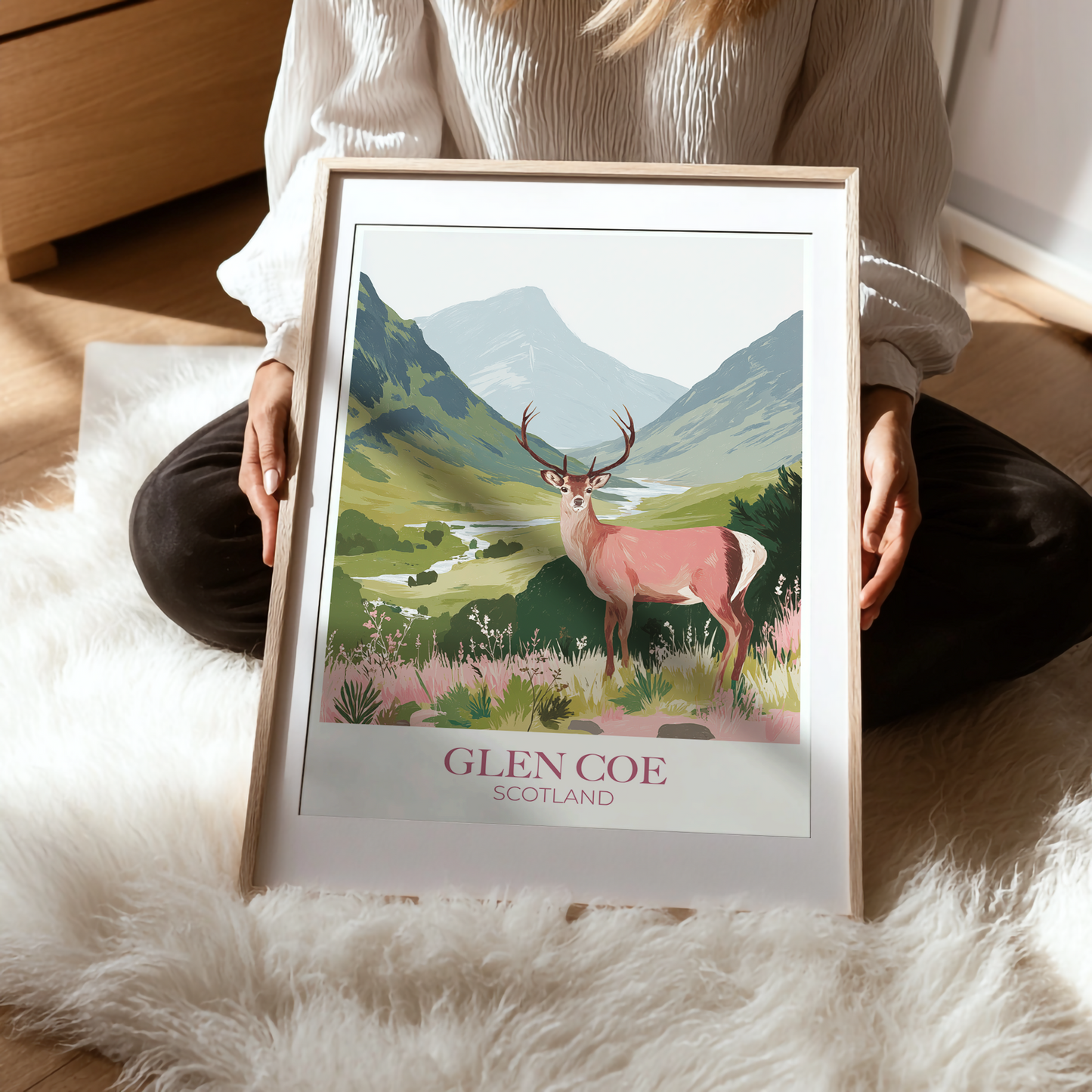 Person holding a framed print of Glen Coe, Scotland with a deer illustration.