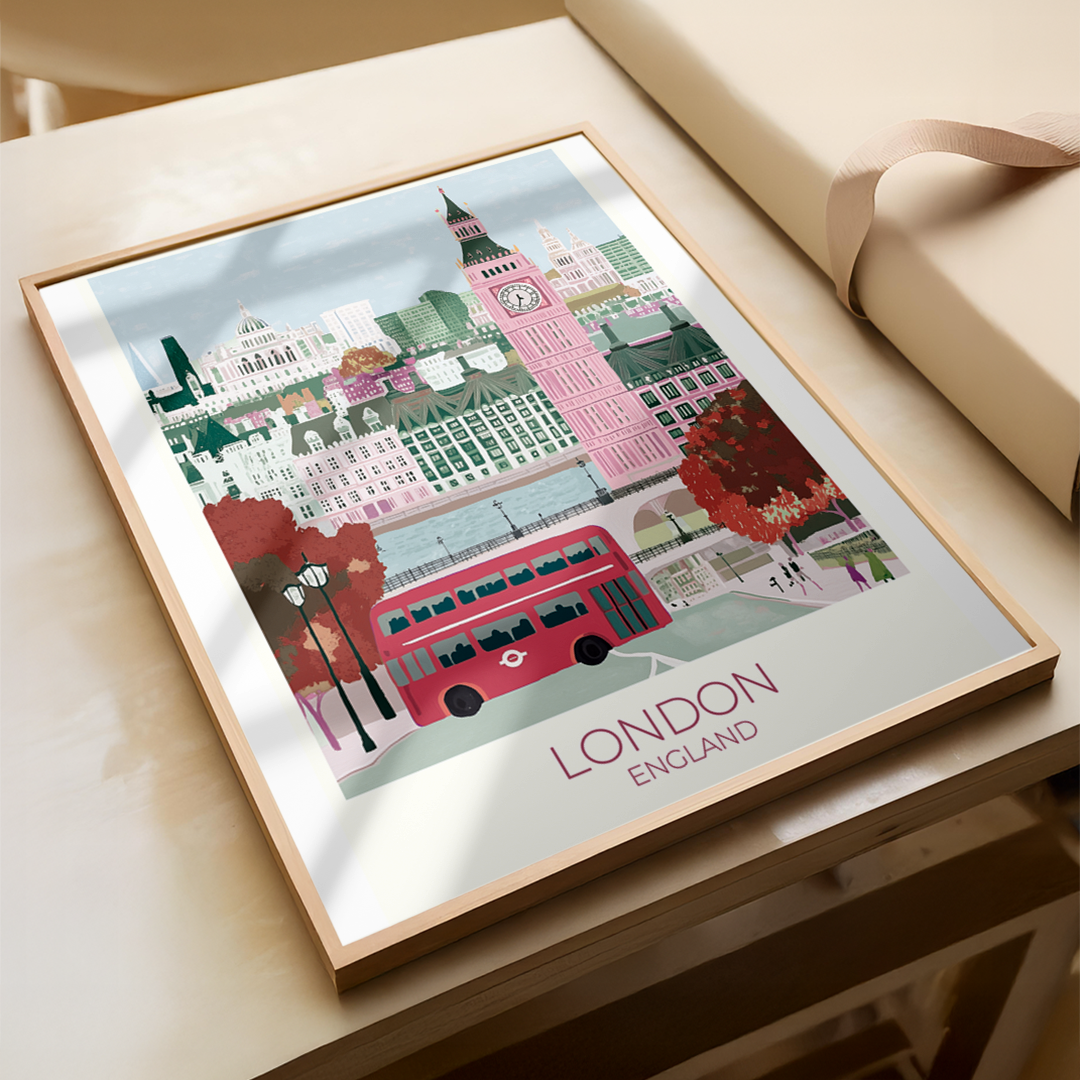Framed artwork of London with Big Ben and a red bus on a wooden surface.