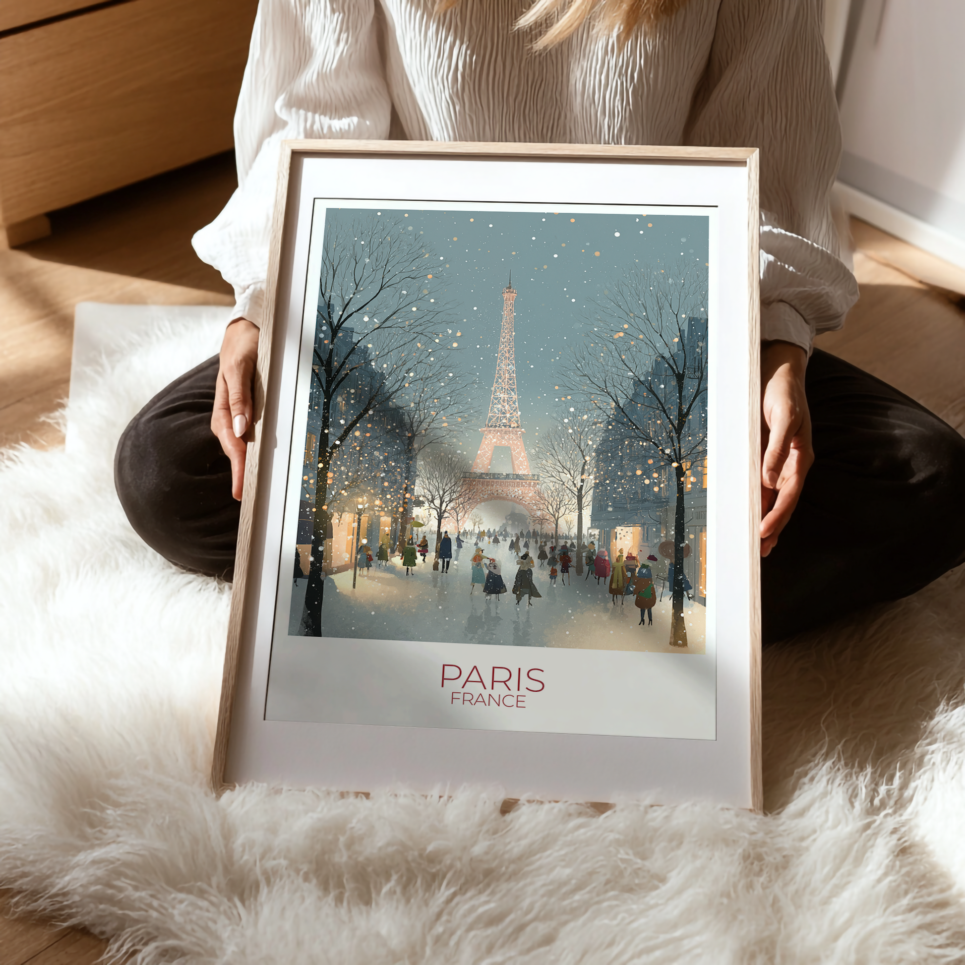 Person holding a framed print of the Eiffel Tower in Paris on a soft surface.