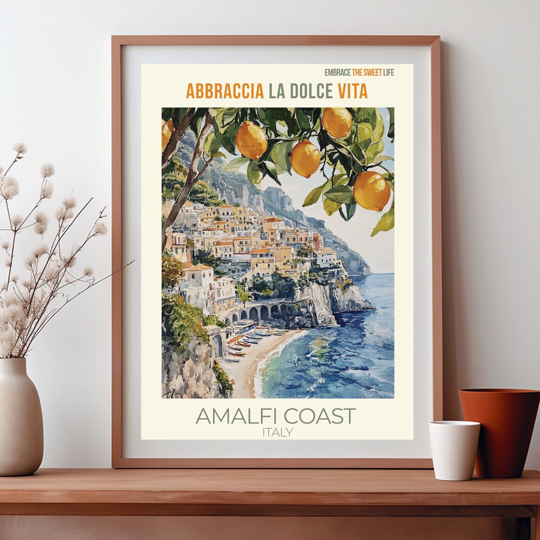 Framed artwork of the Amalfi Coast with 'Abbraccia La Dolce Vita' text on a wooden shelf.