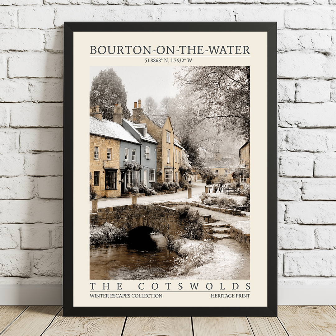 Framed print of Bourton-on-the-Water in the Cotswolds on a white brick wall.