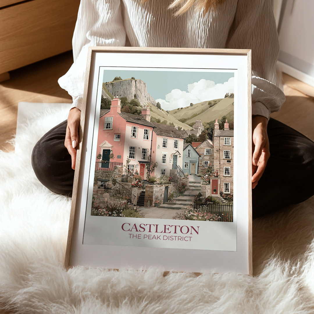 Person holding a framed print of Castleton, The Peak District with a scenic view of houses and a castle.