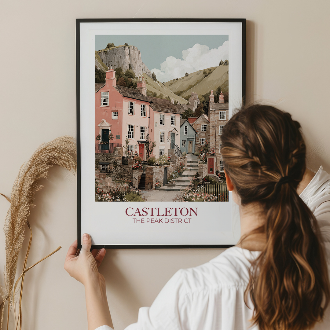Woman holding a framed print of Castleton, The Peak District against a beige wall.