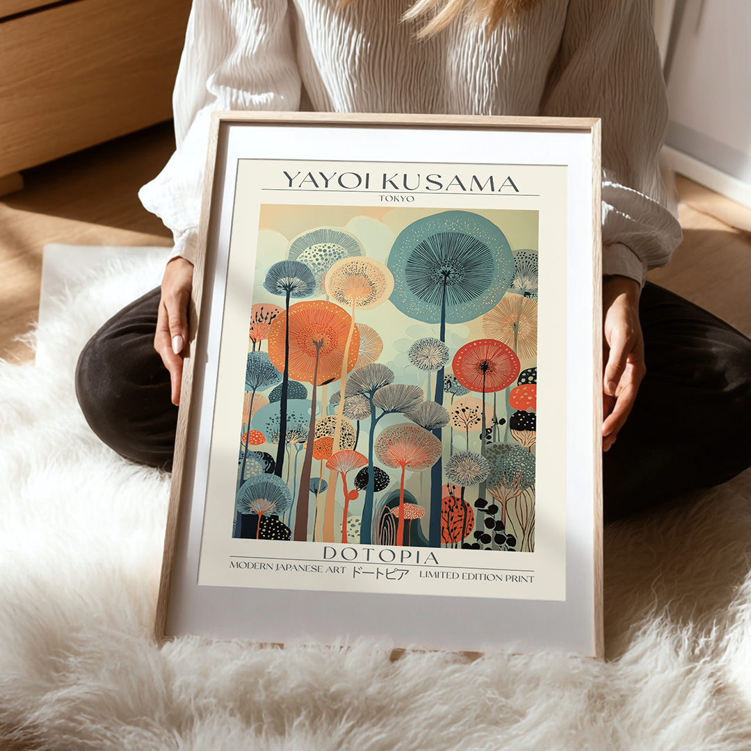 Framed Yayoi Kusama artwork titled 'Dotopia' held by a person on a soft surface.