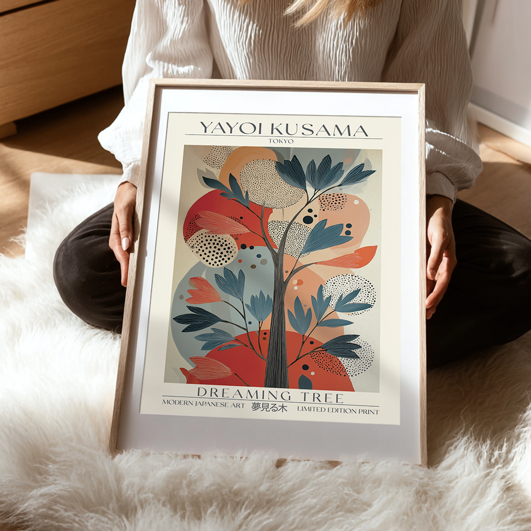 Person holding a framed Yayoi Kusama 'Dreaming Tree' print on a soft surface