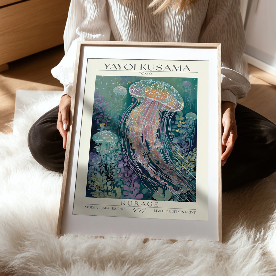 Framed artwork of jellyfish by Yayoi Kusama held by a person on a soft surface.