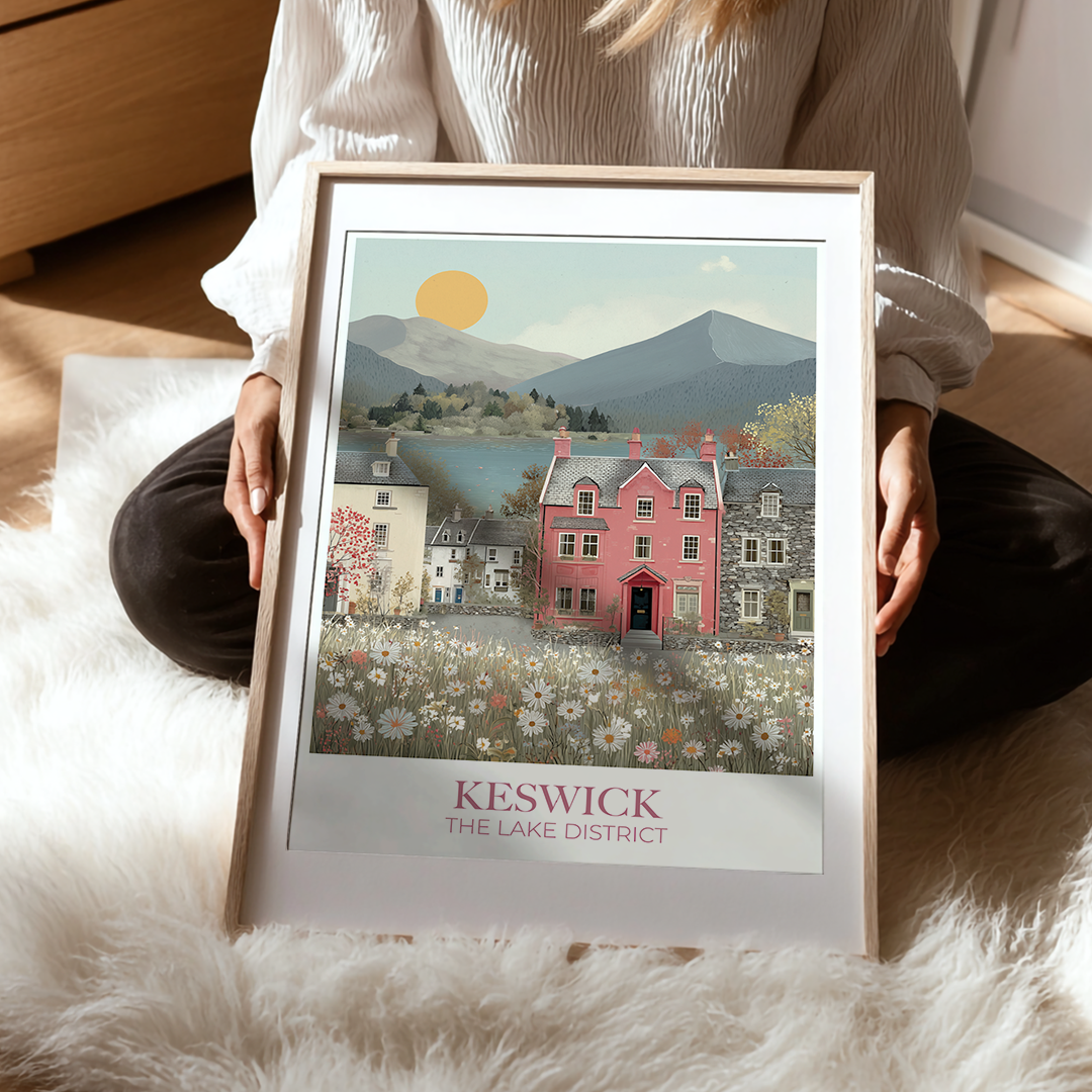 Person holding a framed print of Keswick, The Lake District with a scenic illustration.