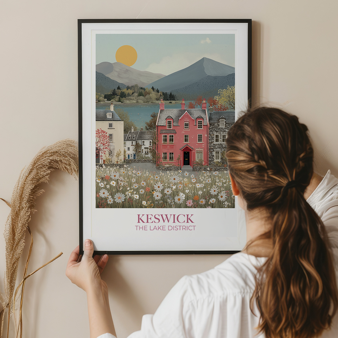 Woman holding a framed print of Keswick, The Lake District against a beige wall.