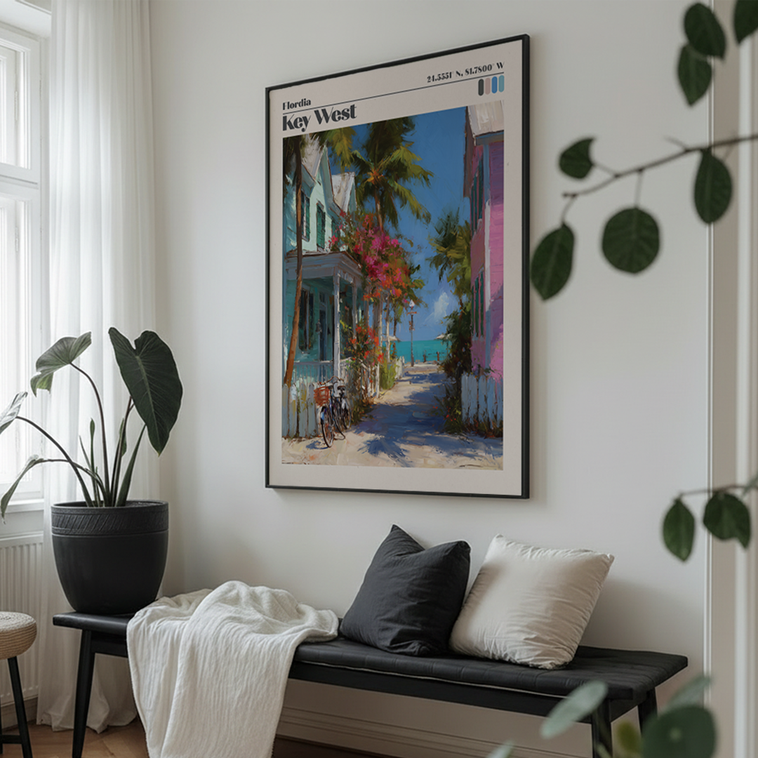 Framed artwork of a tropical street scene on a wall above a bench with cushions.