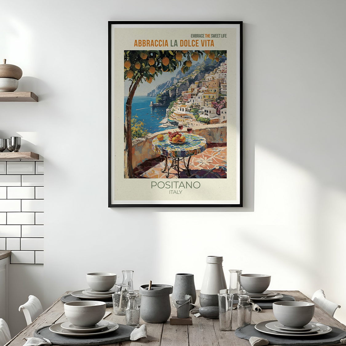 Framed travel poster of Positano on a wall above a dining table with kitchen decor.