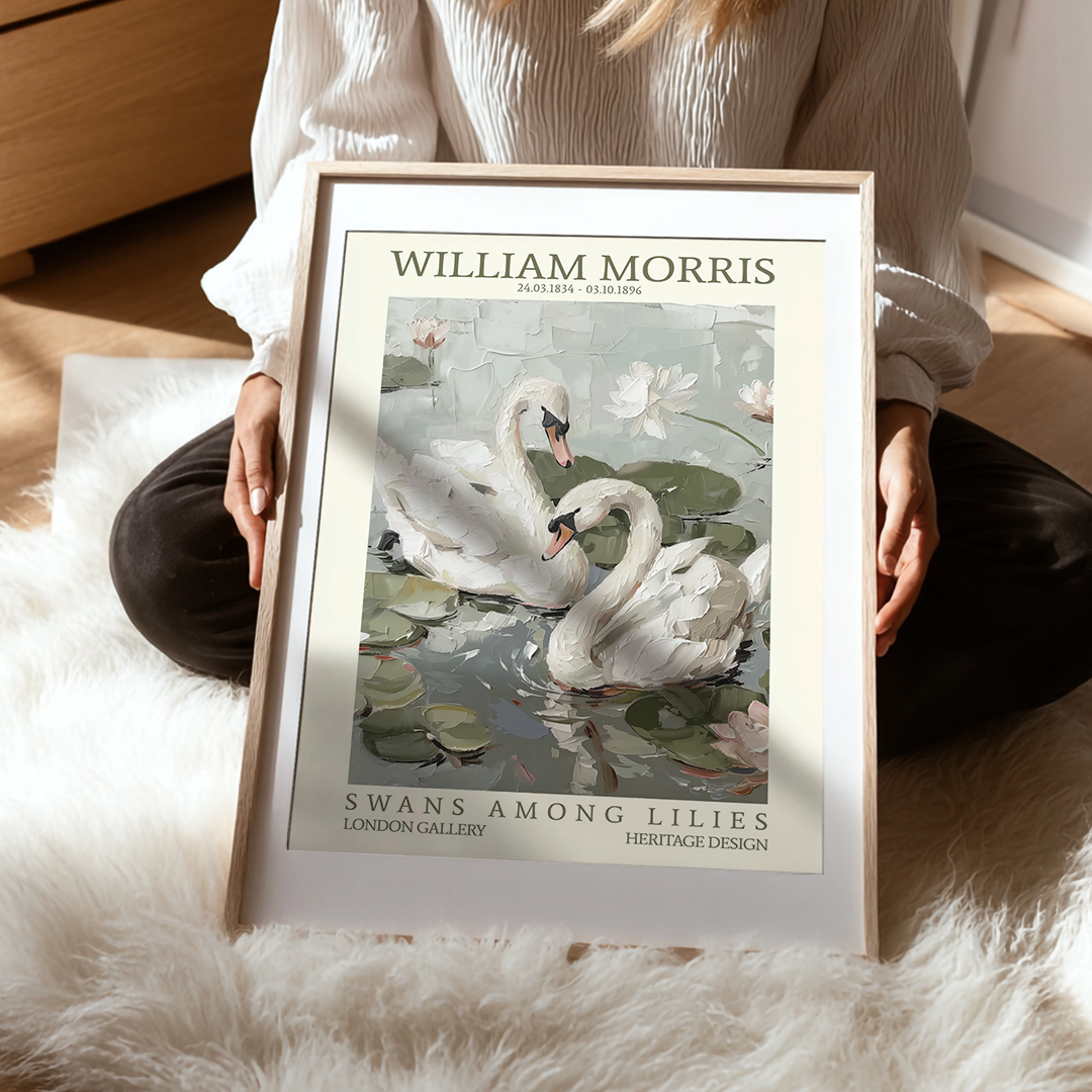 Person holding a framed poster of 'Swans Among Lilies' by William Morris on a soft surface.