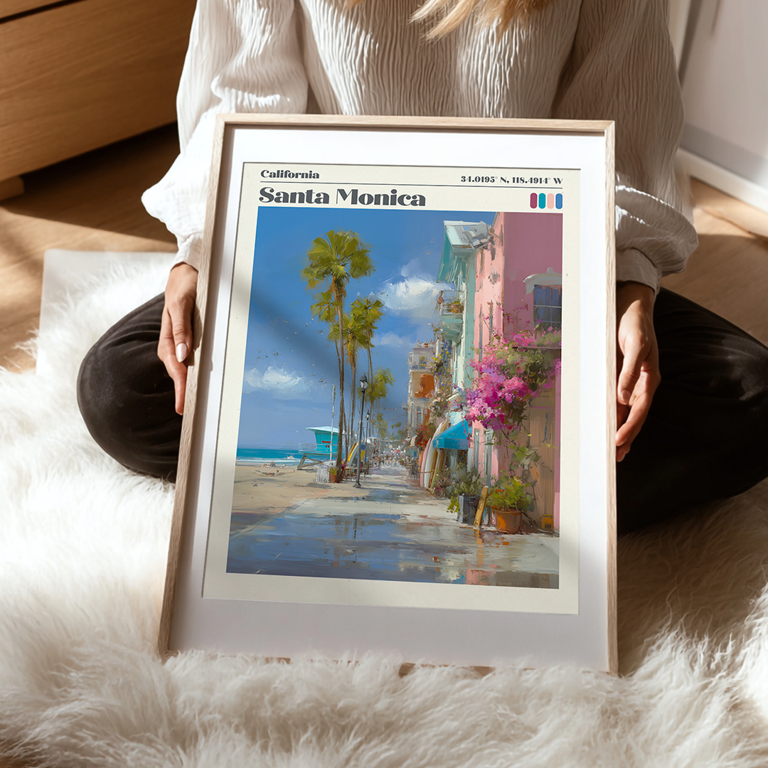 Person holding a framed poster of Santa Monica with palm trees and beach scene.
