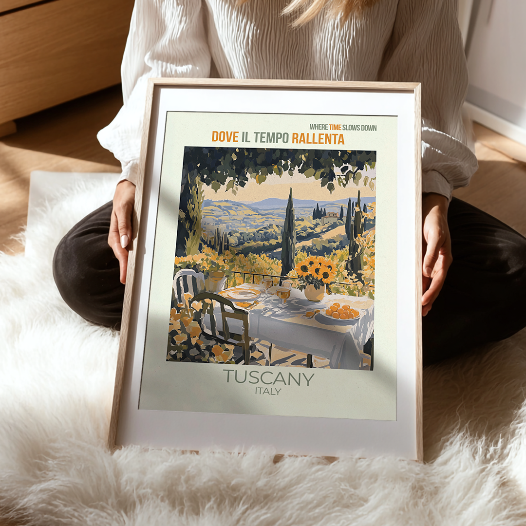 Person holding a framed print of Tuscany with a scenic table setting.