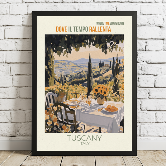 Framed artwork of Tuscany, Italy with a table and chairs on a white brick wall.
