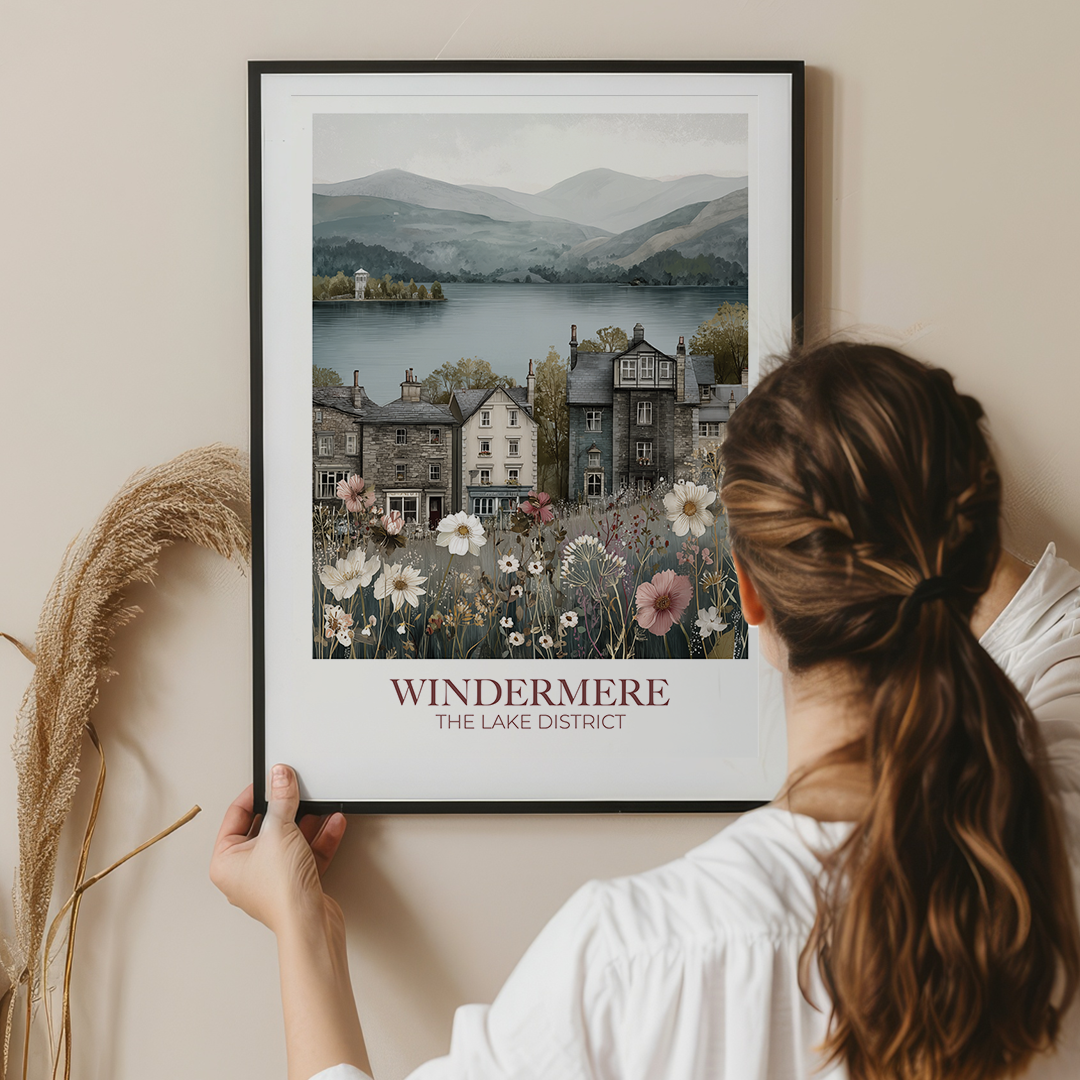 Woman holding a framed print of Windermere, The Lake District against a beige wall.