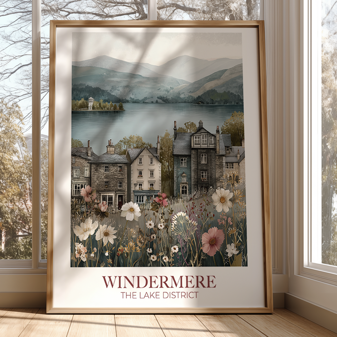 Framed artwork of a lakeside village with 'Windermere' text, displayed in a room with large windows.